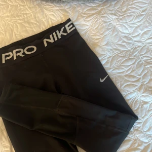 Svarta Nike Pro leggings - Svarta Nike Pro leggings. Sitter tight och är perfekta för träning. Gjorda i stretchigt syntetmaterial. Är i storlek M (barn storlek) är i bra sick men har tyvärr en lim fläck. 