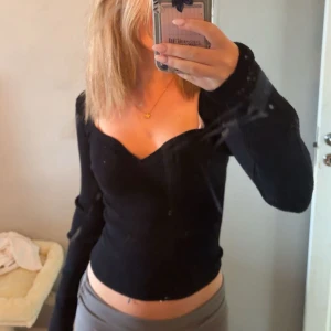 Svart ribbad långärmad topp - Säljer en svart långärmad topp med snygg v-ringad hals och ribbad struktur. 