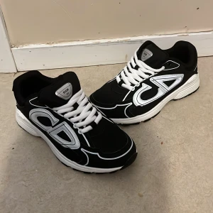Svarta Dior B30 sneakers med vita detaljer - Säljer ett par svarta Dior B30 sneakers med vita och reflekterande detaljer samt tydlig CD-logga på sidorna. Skorna har vit snörning, kan användas som höst eller vinter skor. Pris kan diskuteras 