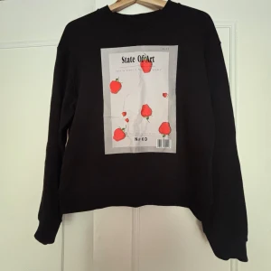Svart sweatshirt från  NA-KD - Cool svart sweatshirt från NA-KD med stort print framtill med jordgubbar och texten 'State Of Art'. Tröjan har rund hals, långa ärmar och relaxed fit. Perfekt för dig som gillar unika prints och streetstyle. Skriv vid frågor 🤩