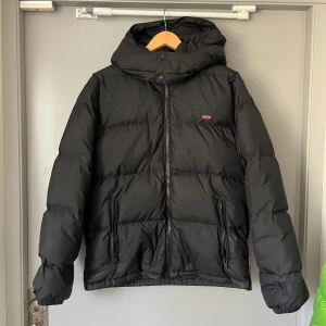 Levis dunjacka - Säljer denns snyhga svarta dunjackan från levis. Använd max 5 gånger så i väldigt fint skick utöver en liten skråma på ryggen som man knappt märker och kan lätt lagas hos skräddaren annars. Köptes ny i New york för 2700kr, säljer den nu till ett kanonpris på endast 699kr