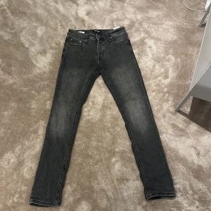 Grå slim jeans från Jack & Jones - Skick: 8/10. Jag säljer mina snygga grå jeans från Jack & Jones i modellen Slim/Glenn. Jeansen har en smal passform, klassisk femficksdesign och är tillverkade i mjukt denimtyg. Perfekta för dig som gillar en stilren och modern look.