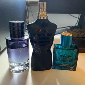 Tre herrparfymer: Dior, Versace, JPG - Mängd syns på bilderna. JPG har lite kvar, kanske 5-10ml. Säljer tre ikoniska herrparfymer: Dior Sauvage i en stilren blå-lila glasflaska, Versace Eros i en turkosblå kvadratisk flaska med Medusa-detalj och metallock, samt Jean Paul Gaultier Le Male i svart kroppformad flaska med silverdetaljer. 
