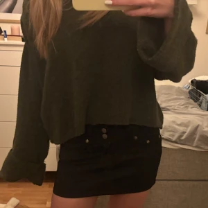 Svart jeanskjol från Goodies - Säljer en svart kort jeanskjol från Goodies med snygga silverknappar och klassiska fickor fram och bak. Kjolen har en tight passform och är perfekt att styla med en oversized tröja eller crop top. Enkel och stilren design som funkar till många looks.