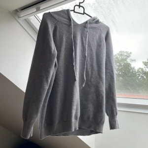 Grå Kashmir hoodie med snörning - Mysig grå Kashmir hoddie i stickat material med huva och snörning.  Perfekt för kyliga dagar när du vill vara både bekväm och stilren. Pris går att diskutera!