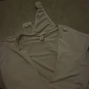 Vit body med djup v-ringning - Säljer en vit bodyfrån H&M med djup v-ringning och långa ärmar. Mjukt och följsamt material för en bekväm känsla. Materialet är lite som satin.  