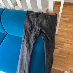 Levi's 501 svarta jeans W34 L32 - Säljer ett par klassiska svarta Levi's 501 jeans i premiumkvalitet. Jeansen har rak passform (liter mer åt den baggy sidan), fem fickor och knappgylf. Tillverkade i slitstarkt bomullsjeans med snygg tvättad finish. Perfekta för dig som gillar tidlös stil och vill ha ett par jeans som funkar till allt. Byxorna är använda, men fortsatt i gott skick och inga skador!