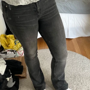 Mörkgrå bootcut jeans - Säljer ett par mörkgrå jeans med bootcut-modell och klassisk femficksdesign. Jeansen har en snygg tvättad look och sitter tajt över låren för att sedan bli vidare nedtill. Perfekta för dig som gillar en stilren men ändå trendig vibe.