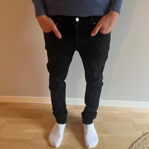 Slim Nudie Jeans, 30/32 - Säljer ett par svarta jeans från Nudie Jeans. De har klassisk femficksdesign, svarta sömmar och Nudie-logga på bakfickan. Jeansen är slim fit och sitter fint hela vägen ner. Perfekta för dig som gillar en clean och stilren look.