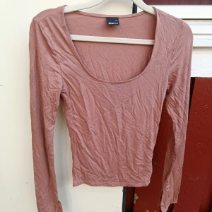 Rosa långärmad topp från Gina Tricot - Säljer en enkel och snygg långärmad topp från Gina Tricot i en dammigt rosa nyans. Toppen har rundad, djup urringning och är tillverkad i mjuk bomull. Perfekt att styla med jeans eller kjol för en chill look.