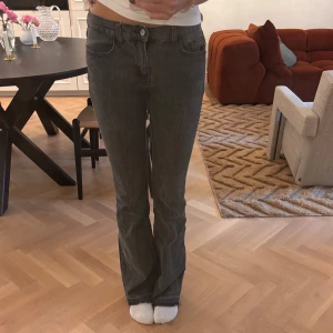 Grå bootcut jeans från Brandy Melville - Säljer ett par grå Brandy jeans med bootcut-modell och råa kanter nertill. Jeansen har klassisk femficksdesign, subtila vertikala ränder och normal passform.
