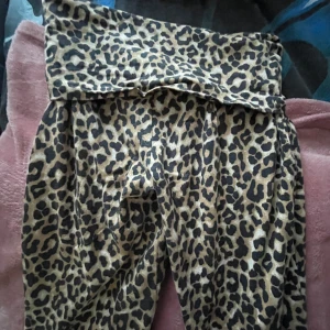 Leopardmönstrade yoga byxor - Säljer ett par yoga byxor med leopardmönster i beige/brun och svart. Byxorna har bred linning och är tillverkade i ett mjukt och stretchigt material, vilket gör dem riktigt sköna att ha på sig. Perfekta för dig som vill sticka ut med en djärv look.❤️