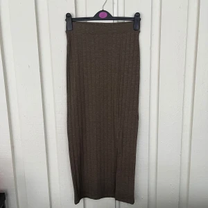 Brun ribbad långkjol från LMTD - Säljer en brun ribbad långkjol från LMTD i modellen 'Chocolate Chip'. Kjolen har en slim passform och en snygg slits på sidan. Perfekt att styla med sneakers eller boots för en chill look.