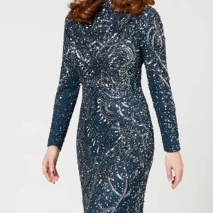 Glittrig marinblå långklänning - Säljer en superglittrig marinblå långklänning med silverpaljetter i snyggt mönster. Klänningen har lång ärm och figurnära passform, perfekt för att sticka ut på festen eller balen. Materialet känns lyxigt och skimrar i ljuset.