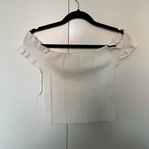 Vit off shoulder tröja - Vit off shoulder tröja från Dilvin i strl XS. Använd fåtalet gånger. (Bandet som hänger ned är ett sånt som man kan hänga på galgen men som gått av)