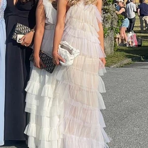 Långklänning från The Bar - Säljer en superfin långklänning i färgen Blanc (ljusrosa) från The Bar. Klänningen har lager på lager av volanger i tyll och en liten slits framtill. Orginalpris är ca 6400kr. Storlek 4. Passar mig som brukar ha storlek 34/36. Endast använd en gång, kan vara lite smutsig längst ner  men inget som inte går att ta bort. Kan skicka bild om så önskas