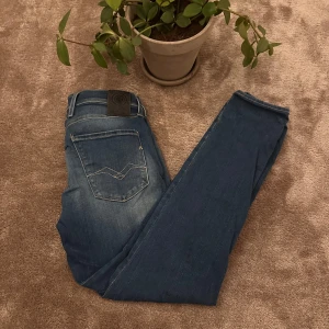 Replay Anbass jeans - Säljer ett par Replay Anbass jeans i klassisk. snygga slitningar och en slim passform. Märkespatch bak i midjan och Replay logga på fickan fram. Perfekta för dig som gillar stilrena jeans med modern känsla.