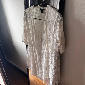 Vit spetsklänning från Lindex - Säljer en vit spetsklänning från Lindex med halvtransparent material och vackra broderade blommor. Klänningen har trekvartsärm och är i en luftig, normal passform. Perfekt för somriga tillfällen!