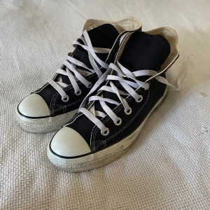Svarta Converse Chuck Taylor All Star - Klassiska svarta Converse Chuck Taylor All Star med vita gummidetaljer och snörning. 