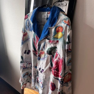 Soulland x Playboy samarbete - silke flerfärgade skjorta, storlek M - Ett unikt samarbete med det danska märket och Playboy från FW19 kollektionen. Denna skjortan har bl.a dokumenterats i Hypebeast tidningen: https://hypebeast.com/drops/playboy-x-soulland-fw19-collection                                               Färgglad skjorta med ett unikt tryck av olika frukter och grönsaker. Skjortan har en klassisk krage i en kontrasterande blå färg och en bröstficka. Perfekt för att lägga till en lekfull touch till din outfit. Skjortan köptes i Köpenhamn för 3895kr 