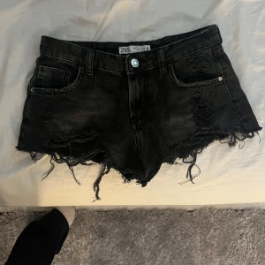 Svarta lågmidjade jeansshorts från Zara - Svarta lågmidjade jeansshorts från Zara med råa fransade kanter och slitna detaljer. Passar till alla sommar toppar i perfekt skick