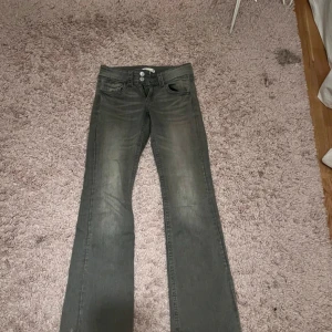 Grå bootcut jeans - Säljer ett par gråa bootcut jeans med klassisk femficksdesign och dragkedja framtill. Jeansen har en lätt tvättad look och raka ben som blir lite utsvängda nertill. Perfekta för dig som gillar en retro vibe.