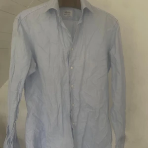 Ljusblå skjorta från Stenströms - Klassisk ljusblå skjorta från Stenströms i fitted body-modell. Skjortan är tillverkad i bomull och har diskret mönster, knappar framtill och lång ärm. Perfekt för en stilren look.