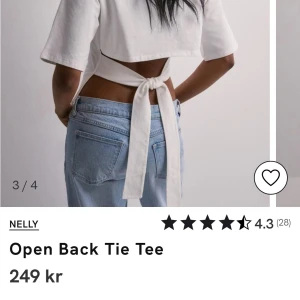 Vit Open Back Tie Tee från Nelly - Säljer en superfin vit topp från Nelly med öppen rygg och knytband. Den är croppad och har korta ärmar, perfekt för sommardagar eller festliga tillfällen. Materialet känns mjukt och skönt mot huden.