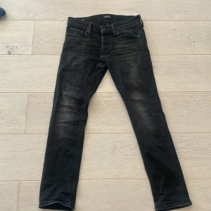 Svarta slim jeans från Jack & Jones - Säljer ett par svarta slim fit jeans från Jack & Jones, modell Glenn. Jeansen har klassisk femficksdesign, dragkedjegylf och lätt tvättad look. Perfekta för dig som gillar en smalare passform och stilren design.
