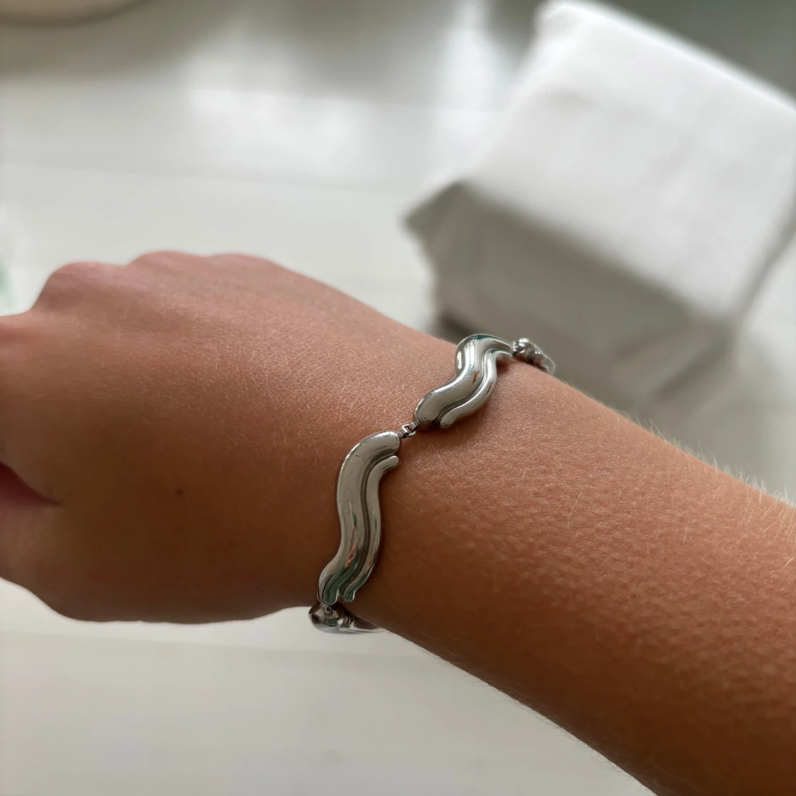Silverfärgat armband med vågformade länkar