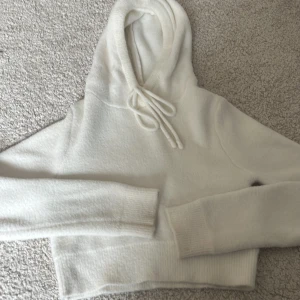 Vit hoodie från Zara - Mysig vit hoodie från Zara med en croppad design och justerbar dragsko i huvan. Perfekt för en avslappnad stil.