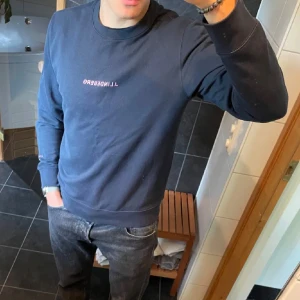 Mörkblå sweatshirt från J.Lindeberg - Säljer en stilren mörkblå sweatshirt från J.Lindeberg med diskret logga på bröstet. Tröjan har rund halsringning och långa ärmar, perfekt för en avslappnad och snygg look.