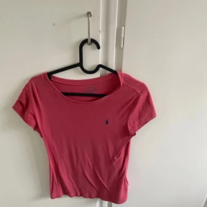 Rosa t-shirt från Polo Ralph Lauren - Säljer en rosa t-shirt från Polo Ralph Lauren med rund halsringning och korta ärmar. Klassisk liten broderad logga på bröstet. Perfekt för en avslappnad och stilren look.