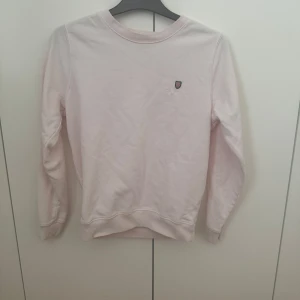 Ljusrosa sweatshirt från Bondelid - Säljer en ljusrosa sweatshirt från Bondelid i storlek S. Tröjan har rund halsringning, långa ärmar och en liten broderad logga på bröstet. Perfekt för en avslappnad och stilren look.