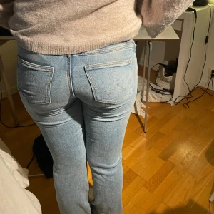 Ljusblå jeansbyxor från Wrangler - Säljer ett par klassiska ljusblå jeans från Wrangler med raka ben och normal passform. Jeansen har tydliga bakfickor med signatursöm och en brun läderpatch med Wrangler-loggan i midjan. Perfekta för en avslappnad stil och sommar look inför sommaren, dock försmå för mig och jag endast har använt fåtal gånger!✨