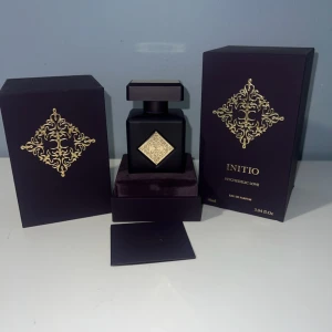 Initio Psychedelic Love Eau de Parfum - Exklusiv parfym från Initio, Psychedelic Love, i en lyxig matt svart flaska med guldfärgade detaljer och fyrkantig form. Kommer i elegant mörklila ask med guldfärgat mönster. Flaskan rymmer 90 ml och har en stilren, modern design som verkligen sticker ut.