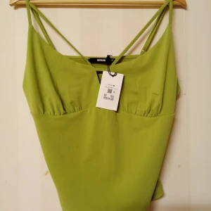 Grön linnetopp från Bik Bok XL - Snygg limegrön linnetopp från Bik Bok i storlek XL. Toppen har tunna dubbla axelband och en liten v-ringning framtill. Tillverkad i mjuk polyesterblandning med lite stretch för skön passform. Perfekt för dig som vill sticka ut med en fräsch färg i garderoben. Kan skickas med extra pris via post.