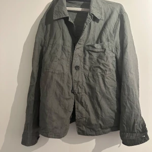 Grön overshirt med knappar - Snygg grön overshirt med klassisk krage och knäppning framtill. Jackan har en bröstficka och två sidofickor, perfekt för en avslappnad och stilren look. Tillverkad i bomull och passar lika bra över en hoodie som till t-shirt.