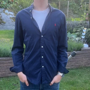 Blå Ralph lauren skjorta - Säljer denna stilrena och snygga blå Ralph Lauren skjorta. Skjortan är i mycket bra skick,  och har QR-kod som fungerar. Modellen är M slim fit. Har du några frågor? Tveka inte att höra av dig. Allt gott från Deluxe garderoben🌟