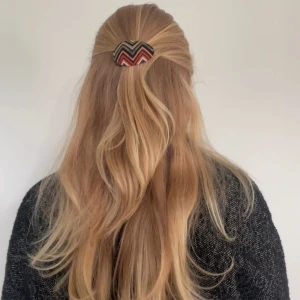 Retro hårspänne med zigzag-mönster - Snyggt ovalt hårspänne med färgstarkt zigzag-mönster i svart, orange, beige och grönt. Perfekt accessoar för att ge din frisyr en cool retrovibe. Spännet är tygklätt och har en unik look som sticker ut.