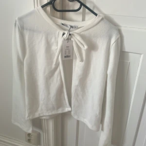 Vit kofta med knyt i bomull - Helt ny vit kofta, i flis material. Från lager 157. Den är lite genomskinlig. 