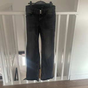 Svarta bootcut jeans från Lindex - Snygga svarta jeans från Lindex i bootcut-modell med medel hög midja och dubbla silverknappar.  Använda 2 gånger.