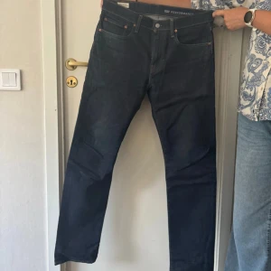 Levi's 502 mörkblå jeans W32 L34 - Säljer ett par Levi's 502 jeans i mörkblå tvätt. Klassisk femficksmodell med raka ben och normal passform. Jeansen är tillverkade i slitstarkt bomullsjeans och har snygga kontrastsömmar samt läderpatch bak i midjan.
