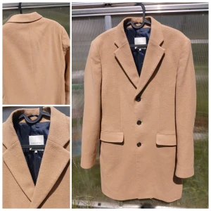 Studio Total Lambton Ullkappa Kamel - Fin kappa ifrån studio total Denna klassiska rock är tillverkad i en ullmix. Två fickor fram med ficklock och två innerfickor. Passformen är normal. Står stl 48 i den enligt sökning är det stl M   Nypris 2300kr