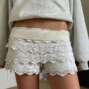 Vita virkade spets-shorts med volanger - Superfina vita shorts med bred resår i midjan och flera lager volangig virkad spets. De har en romantisk och bohemisk vibe med detaljerad spets. Perfekta för sommardagar. Köpta utomlands! Väldigt trendiga och efterfrågade