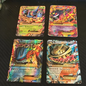 Pokémon EX Mega Collection (4 kort) - Samling med fyra färgstarka Pokémon EX Mega-kort: M Heracross, M Gengar, M Swampert och M Steelix. Perfekt för dig som vill boosta din samling eller spela med unika och kraftfulla kort. Kortens skick varierar, se bilder för detaljer. Skriv vid frågor priset kan diskuteras.
