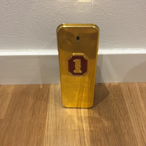 1 Million Parfym från Paco Rabanne - Säljer en 1 Million parfym från Paco Rabanne. Flaskan är rektangulär med en lyxig guldfärgad framsida och detaljer i rött, samt mörk baksida. Designen påminner om en guldtacka och ger en exklusiv känsla. Perfekt för dig som gillar statement-dofter. Det är ungefär 75 ml kvar 