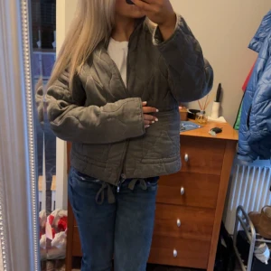 Grön/grå quiltad jacka från Zara - Quiltad grå jacka från Zara i manchester med dragkedja och snörning i midjan. Jackan har en loose passform, långa ärmar och coola vågformade sömmar. Perfekt för dig som vill ha en trendig och bekväm look till hösten eller våren. Pris går att diskutera!!🥰