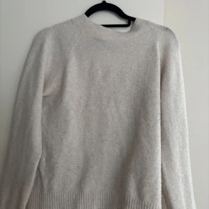 Beige stickad tröja med rund hals - Mysig beige stickad tröja med rund halsringning och ribbade muddar. Perfekt för lager-på-lager och passar till allt. Långärmad och enkel design som är lätt att matcha med jeans eller kjol.