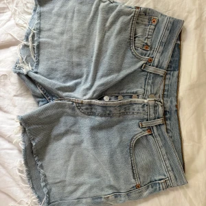 Levi's ljusblå jeansshorts - Ljusblå jeansshorts från Levi's. Shortsen har medel midja och synliga knappar framtill. Perfekta för sommaren och har den ikoniska Levi's-lappen bak i midjan